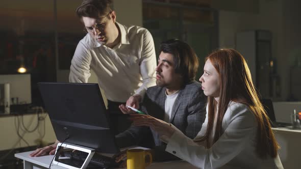 A Team of Young People Works Hard Late at the Office at the Computer Works Overtime alt