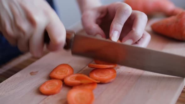 Female Hands Cutting Carrot on a Cutting Board