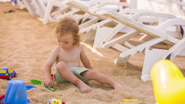 Little Boy Plays With Toys In Sand 