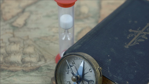 A Compass Hourglass and a Bible on a Map
