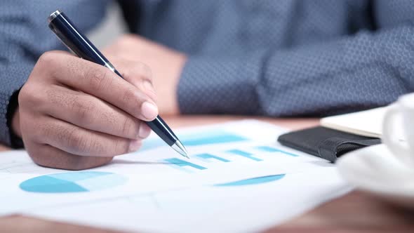 Man Hand with Pen Analyzing Bar Chart on Paper alt