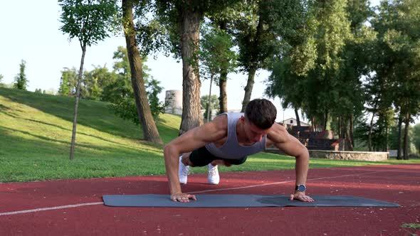 Strong Man Doing Pushups with Clapping on Fitness Mat in Park Sport alt