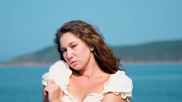 girl in a white sundress on the background of the sea on a bright sunny day