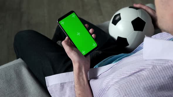Football Fan Use Smartphone at Home with Green Chroma Key Screen