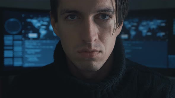 Portrait of Hacker Programmer Looking at Camera in Cyber Security Center Filled with Display Screens