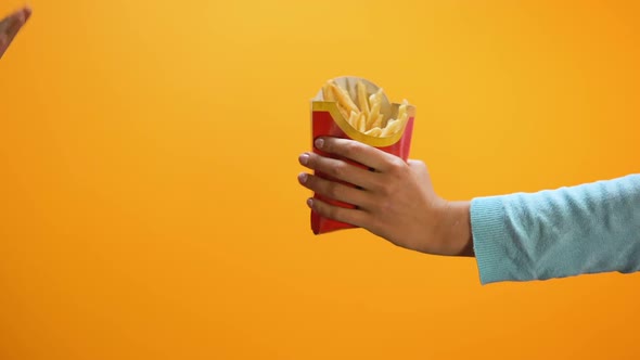 Female Hand Showing Stop Gesture on Yellow Background, Refusing Eat French Fries alt