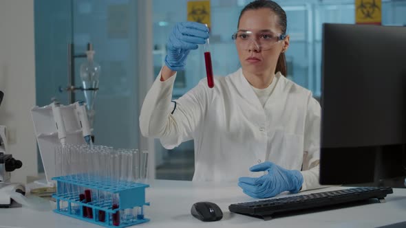 Woman Scientist Looking at Dna Substance in Test Tube alt