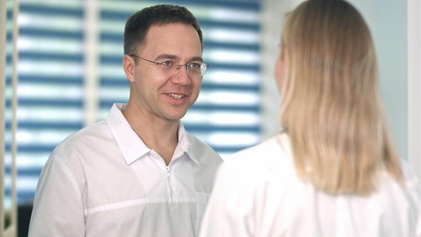 Smiling male doctor in glasses talking to female nurse