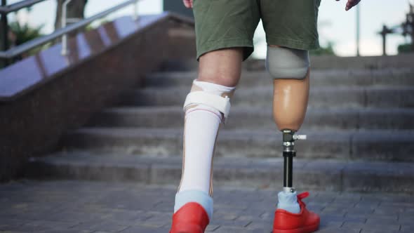 Live Camera Follows Steps of Male Amputee with Prosthesis Walking Upstairs Outdoors alt
