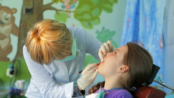 Dentist Fitting And Measuring Braces In Girls