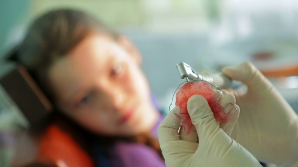 Girl Watching Orthodontist Correcting Braces For