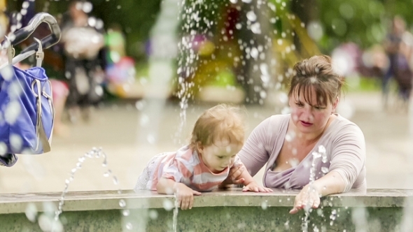 Mother And Baby Enjoying Fountains In The Park