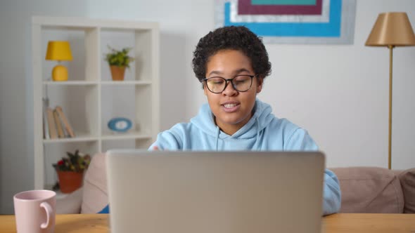 Young African Woman Sitting at Home and Using App on Laptop for Video Call alt
