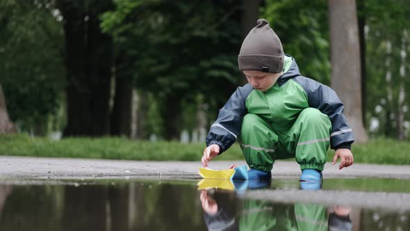 Funny Kid in Rain Boots Playing in a Rain Park alt