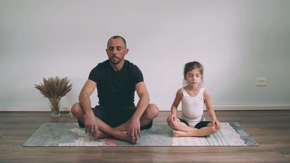Caucasian Man with a Girl Doing Yoga Online Dad and Daughter Sitting in the Lotus Position Yoga for