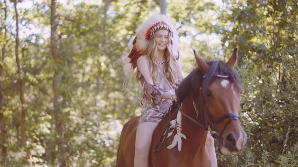 Smiling Woman In Headdress Sitting On Horse In Sunlit Forest alt