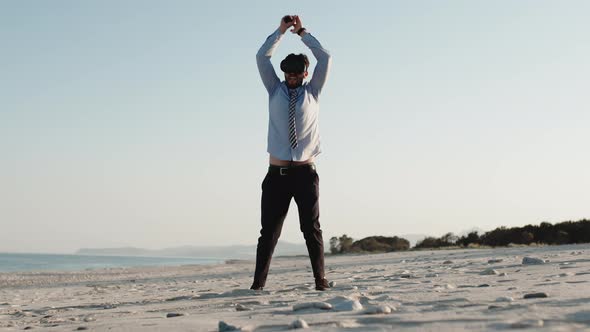 Business Guy Does Sport on the Beach with Virtual Reality Headset and Shirt alt
