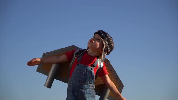 Happy child with toy paper jet pack playing against blue sky