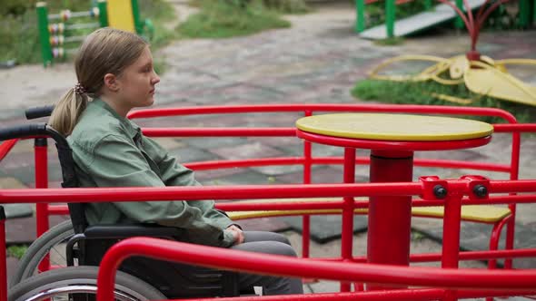 Lonely Sad Disabled Caucasian Girl in Wheelchair Spinning on Merry Go Round in Slow Motion alt