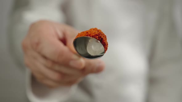 Chef Sprinkles Red Pepper Powder From A Spoon