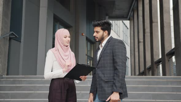 Arab Businessman Signing Papers on Clipboard That Holding Charming Woman in alt