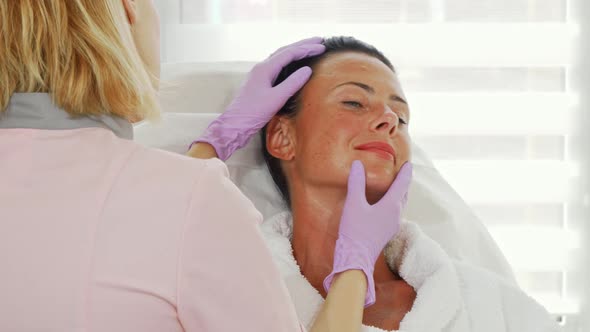 Professional Cosmetologist Examining Face of Her Female Client alt