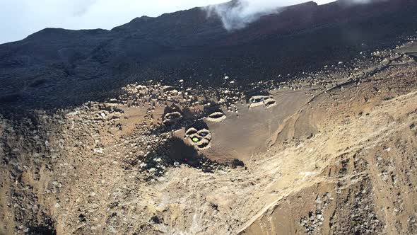 Drone footage of tent in rocks circle on the summit of the Piton des Neiges at the Reunion island. alt