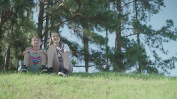 Children sitting together on hillside looking at view alt