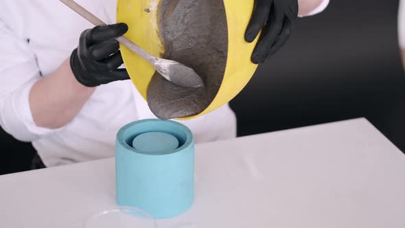 Person Pours Mixture for Modeling Into Blue Stencil alt