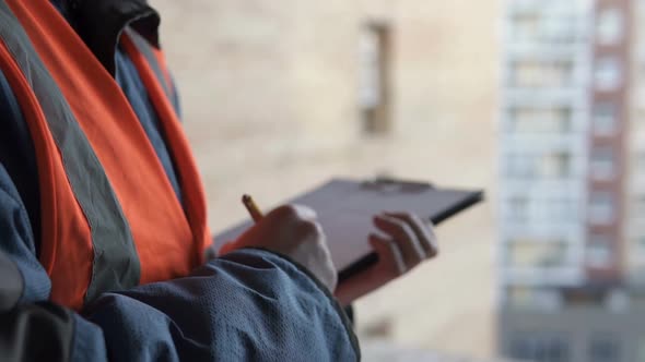 A civil engineer is working with blueprints at the construction site of a high-rise building. alt