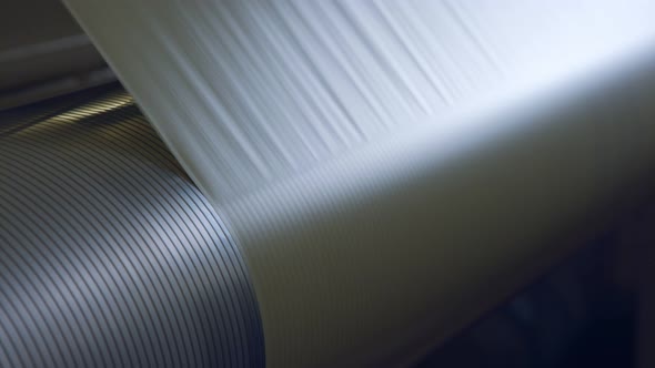 Closeup on paper moving through a large industrial printing machine alt