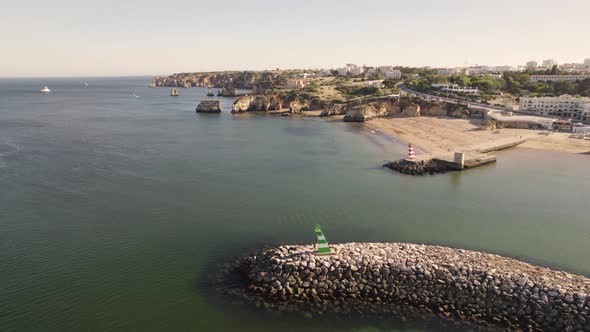 Aerial of the entrance to the Bensafrim River in Lagos, Portugal solitified by heavy wave breakers alt