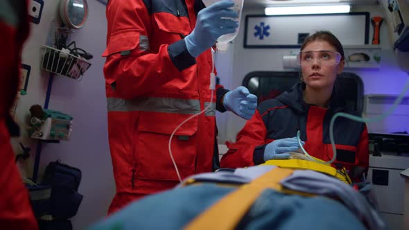 Mixed Race Paramedics Taking Care About Patient on Stretchers in Ambulance Car alt