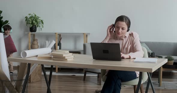 Young Lady Working Remotely From Home on Video Conference When Son Rushes Up and Distracts and