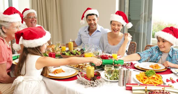 Siblings pulling a christmas cracker at the dinner table 4k alt