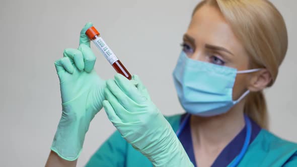 Medical Doctor Nurse Woman Wearing Protective Mask and Gloves - Holding COVID-19 Blood Test alt