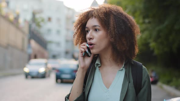 Angry Curlyhaired Black Girl Tourist with Backpack Walks Along Street Yelling at Interlocutor alt