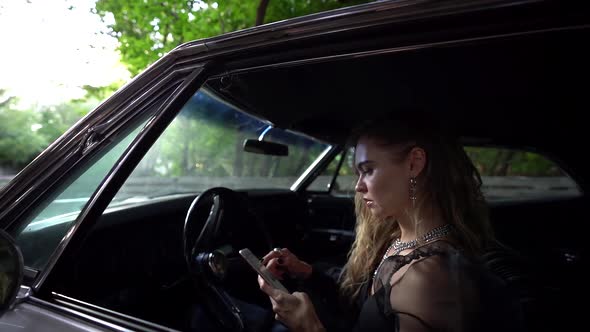 Sorrowful Woman Is Reading Messages in Smartphone and Suffering, Sitting Inside Expensive Car alt