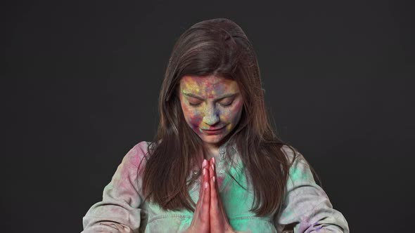 Portrait of Lovely Woman Covered with Multicolor Paint Putting Hands Together on Happy Holi Festival alt