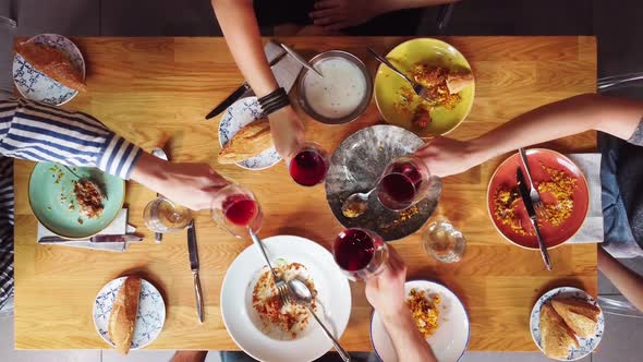 Top View of a Group of Friends Having a Meal Toasting with Wine At Wooden Table alt