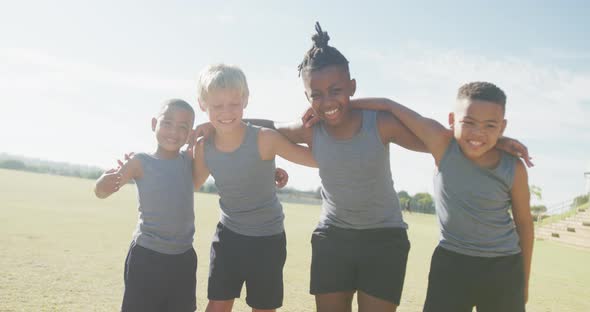 Video of happy diverse boys walking on grass and holding arms alt