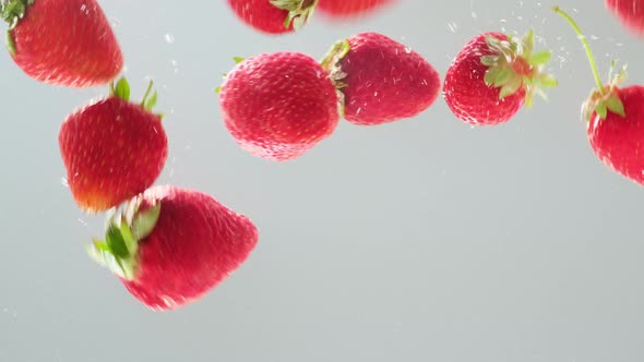 Red strawberry berry falling into transparent water on white background ...