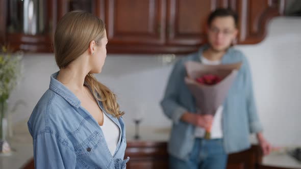 Young Offended Woman Looking Back at Blurred Man with Bouquet of Flowers Turning Crossing Hands alt
