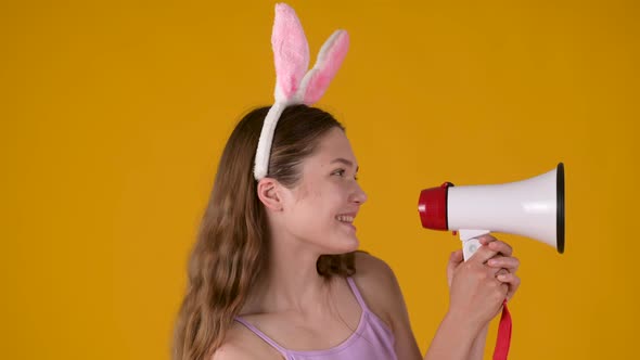 happy young girl in pink bunny ears talking with megaphone