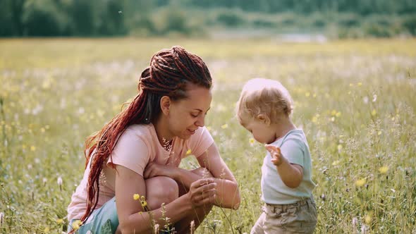 Mom with a child are sitting in a clearing or park. Parenting Maternity Joy Family Concept. alt