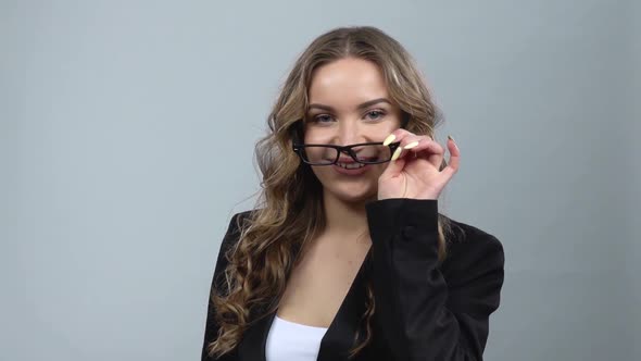 Portrait of Girl with Curly Hair in Bussines Suit Fixing Her Glasses and Winks, Slow Motion alt