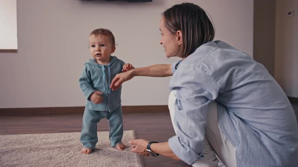 Lovely Caucasian Baby Biy Learning to Walk Taking First Step Walk to His Mother at Home alt