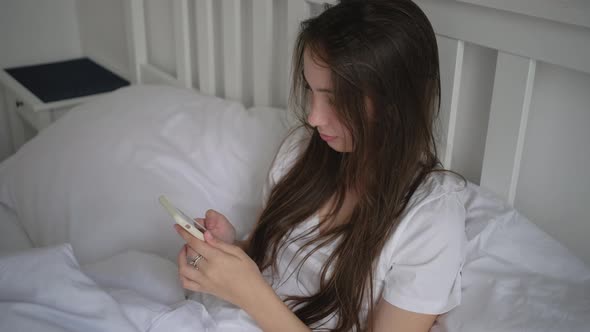 Young Woman Staying in Bed on Her Day Off and Using Mobile alt