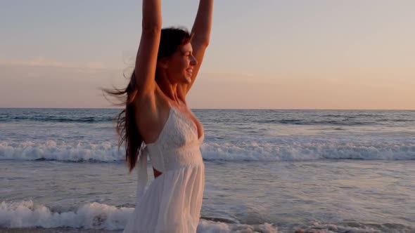Beautiful woman in a white dress at the beach at sunset alt