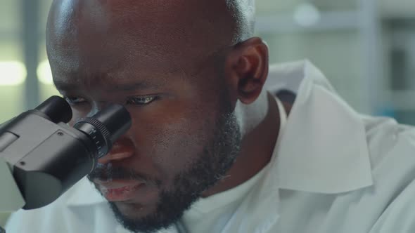 African American Lab Worker Using Microscope alt